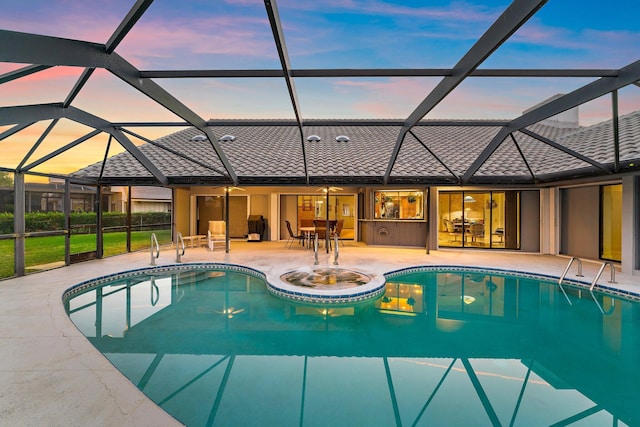 pool at dusk featuring a lanai and a patio area