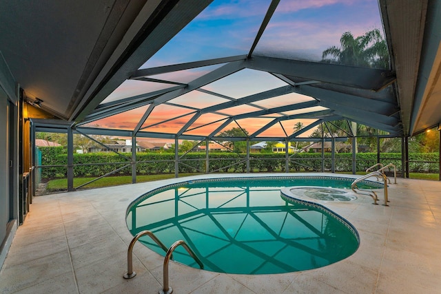 pool at dusk with a patio area, an in ground hot tub, and glass enclosure