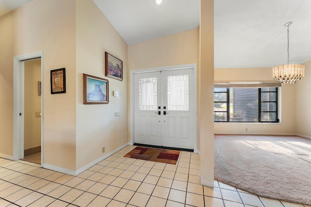 carpeted foyer featuring a notable chandelier, high vaulted ceiling, and french doors