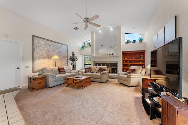 living room featuring a tiled fireplace, ceiling fan, light colored carpet, and high vaulted ceiling