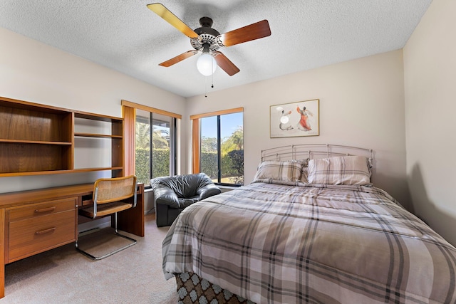 bedroom with built in desk, light colored carpet, ceiling fan, and a textured ceiling