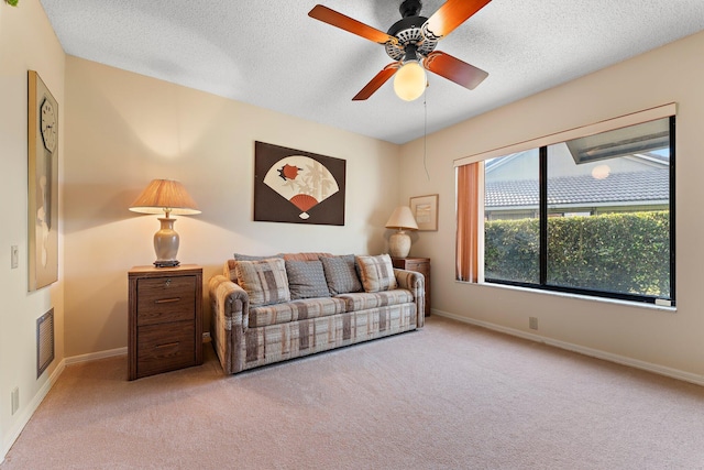 carpeted living room featuring ceiling fan and a textured ceiling