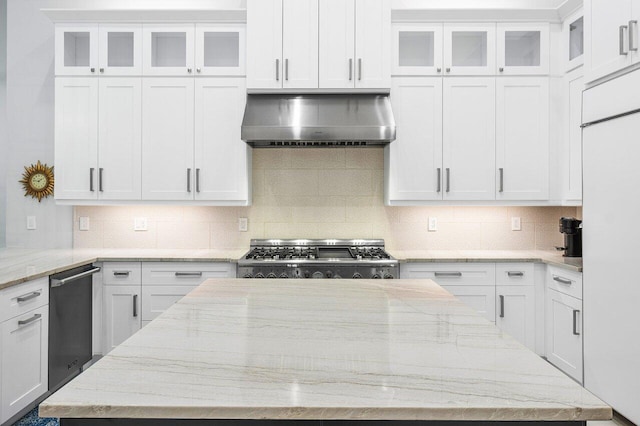 kitchen with white cabinets, stove, wall chimney range hood, and light stone counters