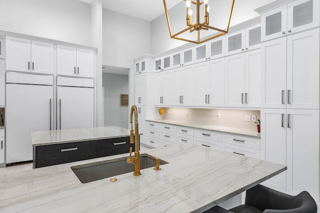 kitchen featuring light stone countertops, pendant lighting, a center island, and white cabinetry