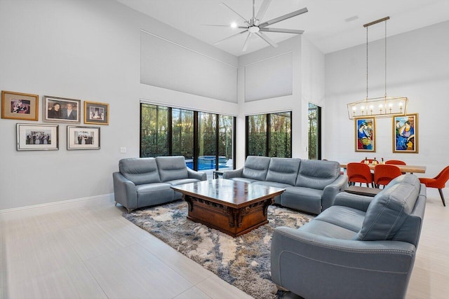 living room with a high ceiling, ceiling fan with notable chandelier, and plenty of natural light