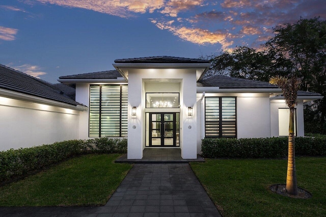 exterior entry at dusk with a lawn and french doors