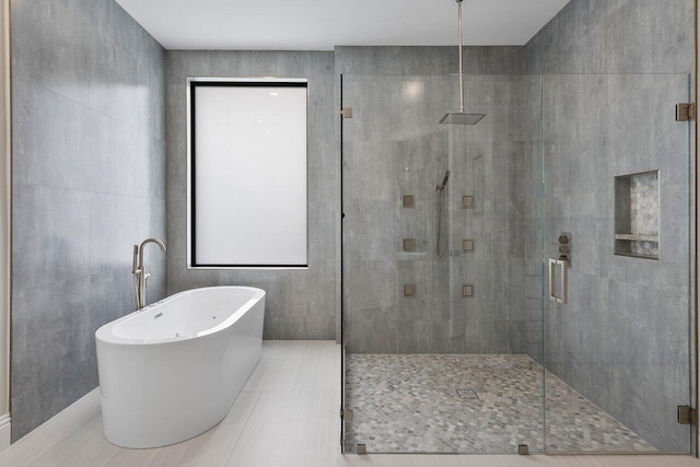 bathroom with tile patterned flooring, tile walls, and independent shower and bath