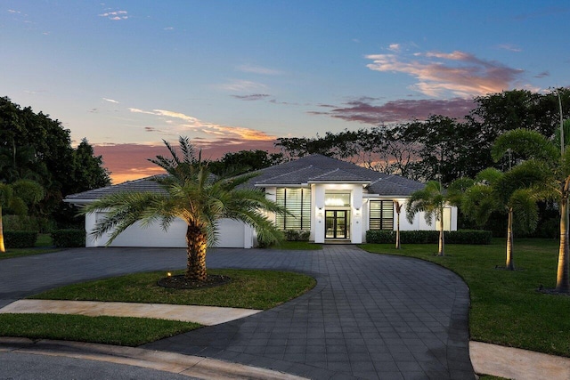 view of front of house featuring a lawn, a garage, and french doors