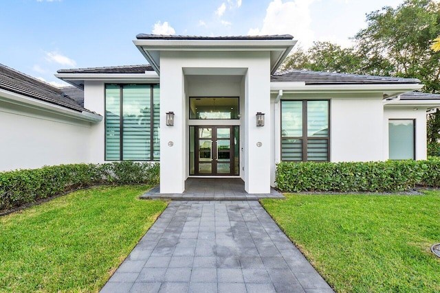 entrance to property with a lawn and french doors