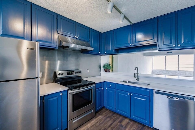 kitchen with blue cabinets, rail lighting, sink, a textured ceiling, and stainless steel appliances