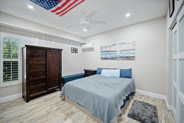 bedroom featuring ceiling fan, light hardwood / wood-style floors, and a wall unit AC