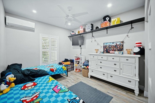 bedroom with light wood-type flooring, a wall unit AC, and ceiling fan