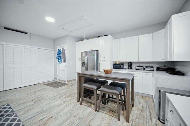 kitchen with light wood-type flooring, white cabinetry, and stainless steel refrigerator with ice dispenser