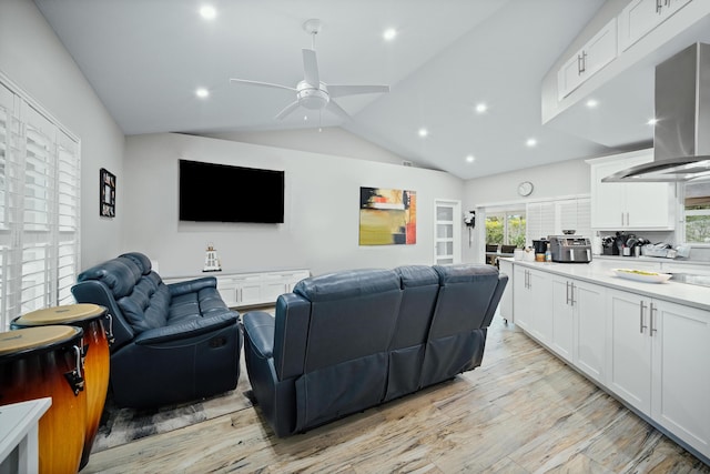 cinema with light wood-type flooring, vaulted ceiling, and ceiling fan