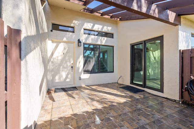 view of exterior entry featuring a pergola and a patio area