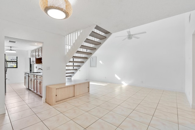 staircase featuring tile patterned floors, ceiling fan, sink, and a textured ceiling