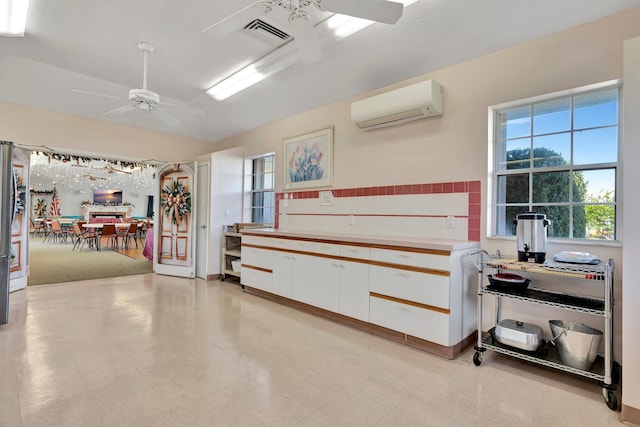 garage featuring an AC wall unit, stainless steel refrigerator, and ceiling fan