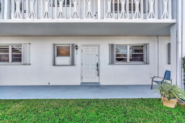 property entrance featuring a balcony and stucco siding