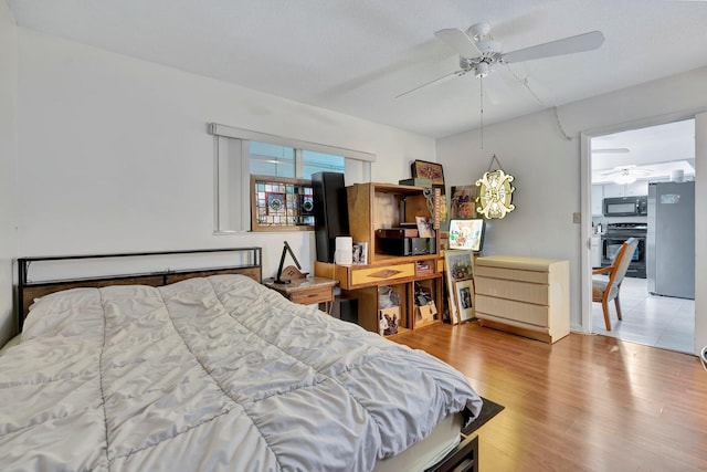 bedroom featuring ceiling fan, stainless steel fridge, light wood-type flooring, and a textured ceiling