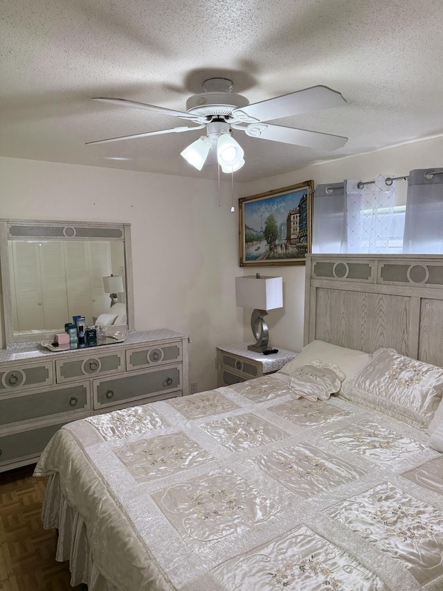 bedroom with dark parquet flooring, ceiling fan, and a textured ceiling