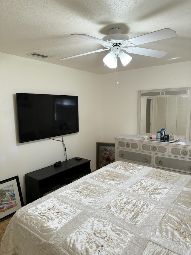 bedroom with ceiling fan and a textured ceiling