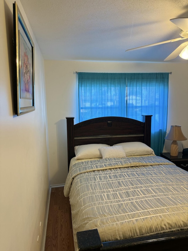 bedroom with hardwood / wood-style flooring, ceiling fan, and a textured ceiling