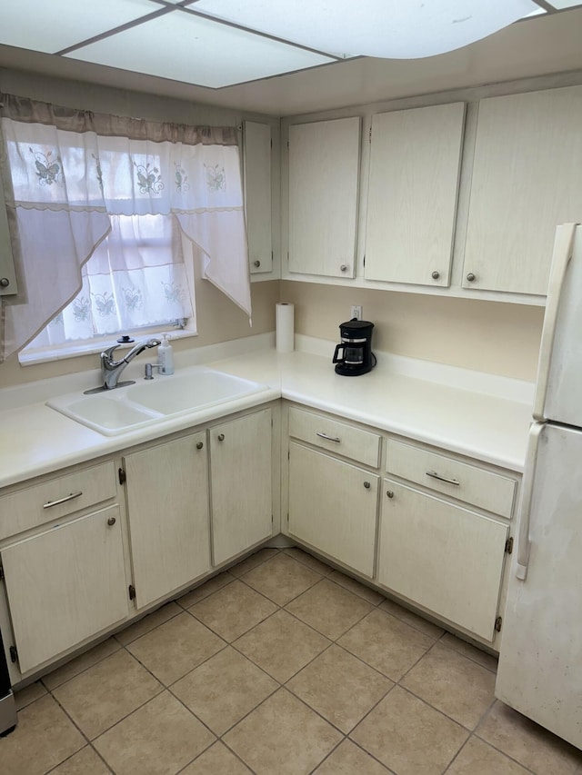 kitchen with light tile patterned floors, white refrigerator, and sink