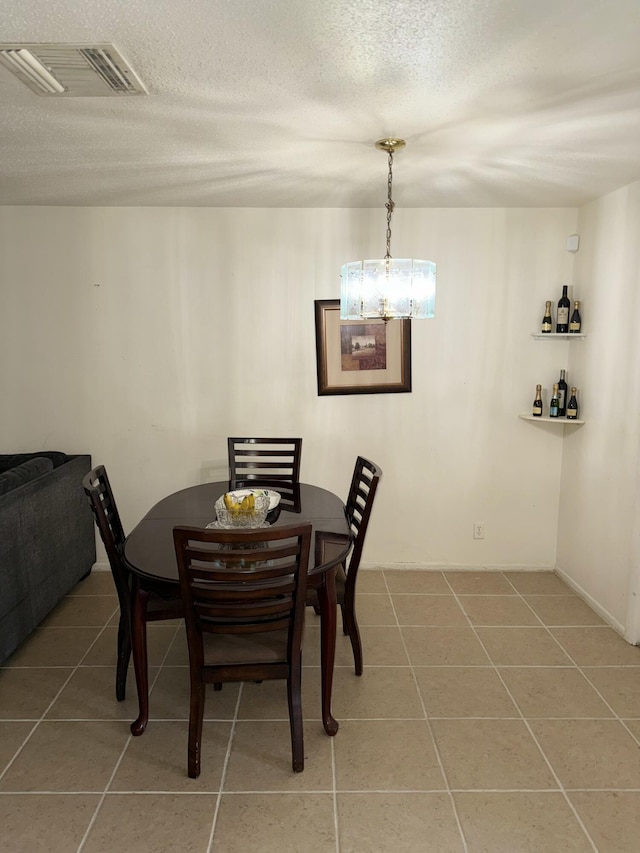 dining space featuring tile patterned floors, a textured ceiling, and a notable chandelier