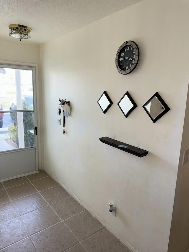 interior space featuring washer hookup, light tile patterned flooring, and a textured ceiling