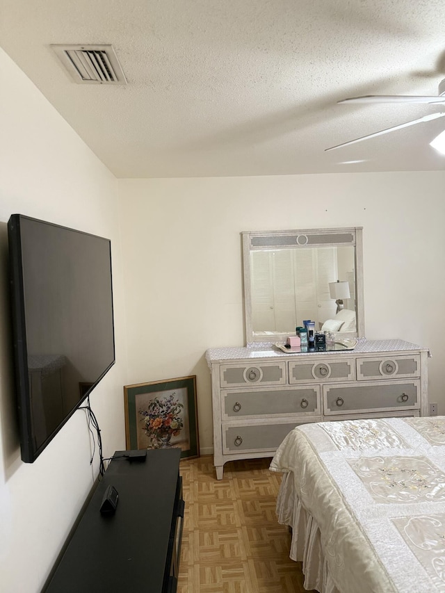 bedroom with a textured ceiling, light parquet floors, and ceiling fan