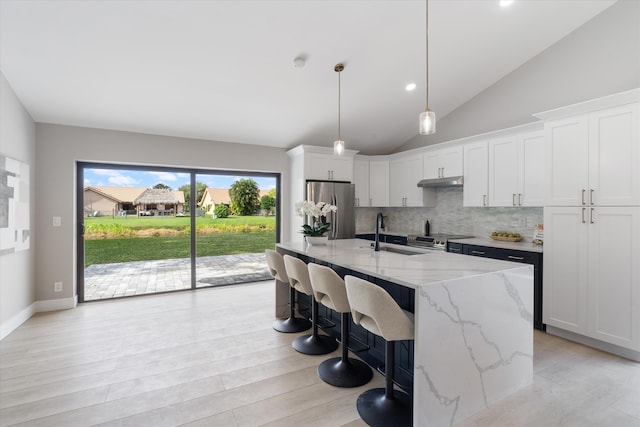 kitchen with white cabinetry, sink, an island with sink, decorative backsplash, and appliances with stainless steel finishes