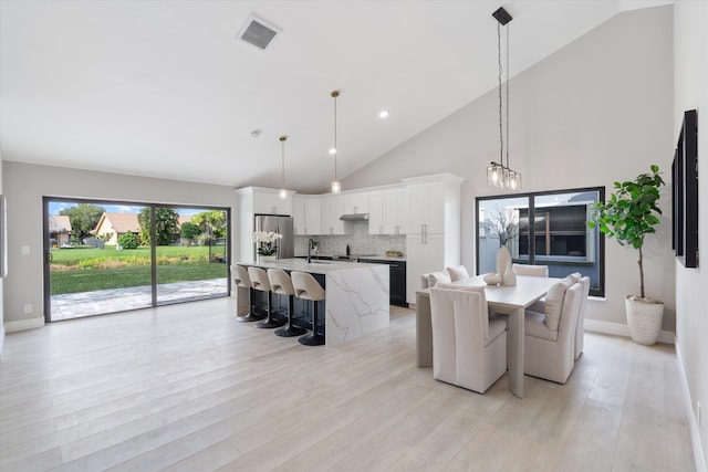 dining space featuring light hardwood / wood-style floors, high vaulted ceiling, and sink