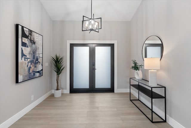 entrance foyer with french doors, light wood-type flooring, and a notable chandelier