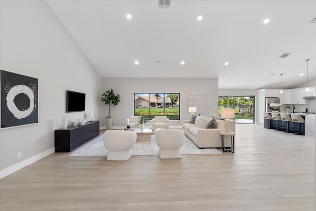 living room with light hardwood / wood-style floors, sink, and high vaulted ceiling