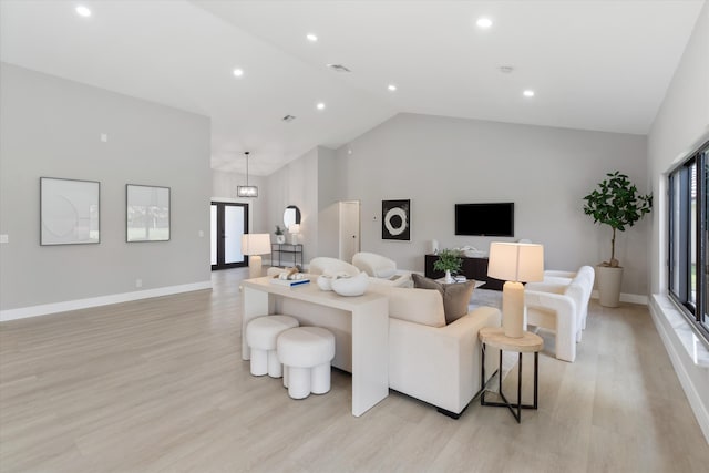 living room featuring light wood-type flooring, high vaulted ceiling, and an inviting chandelier