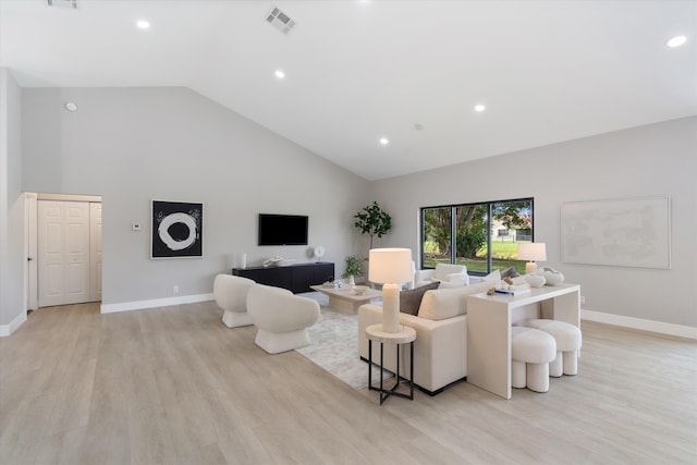 living room featuring high vaulted ceiling and light hardwood / wood-style flooring