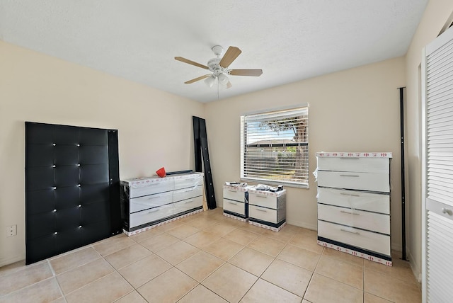 unfurnished bedroom with ceiling fan, a closet, light tile patterned floors, and a textured ceiling