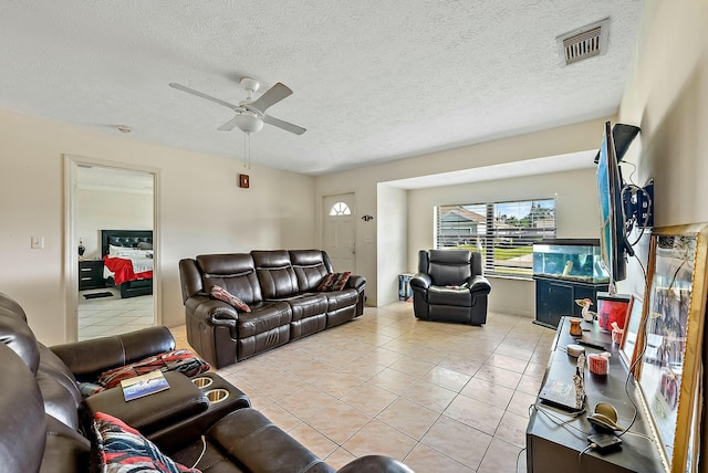 living room with ceiling fan, light tile patterned flooring, and a textured ceiling