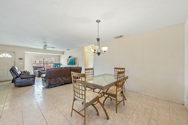 tiled dining space with a textured ceiling and ceiling fan with notable chandelier