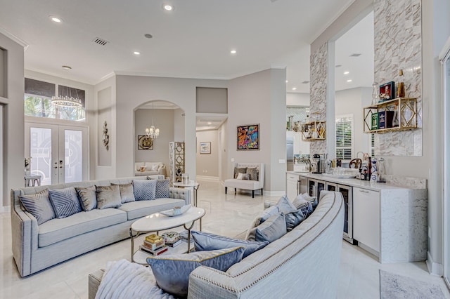 living room featuring a chandelier, sink, ornamental molding, and french doors