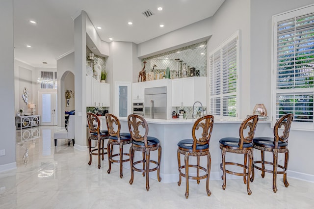 kitchen with a breakfast bar, kitchen peninsula, appliances with stainless steel finishes, and white cabinetry