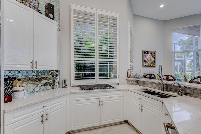 kitchen with light stone counters, sink, white cabinets, and stainless steel gas stovetop