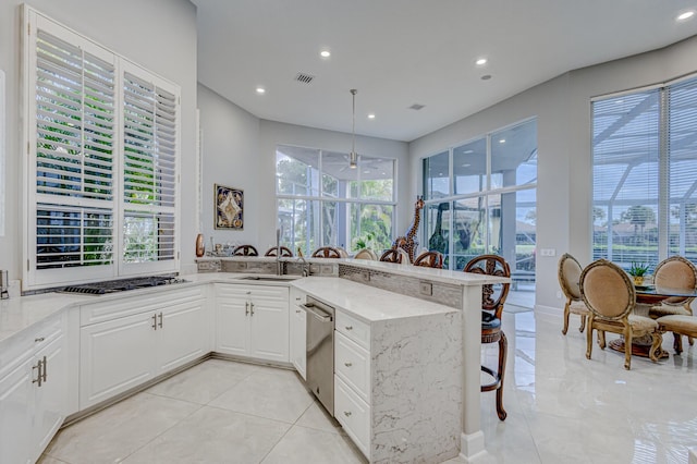 kitchen featuring a breakfast bar, kitchen peninsula, white cabinetry, stainless steel gas cooktop, and light stone counters