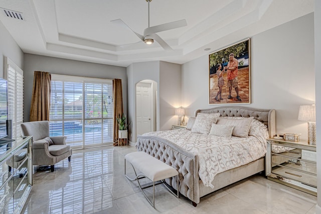 bedroom with ceiling fan, access to exterior, and a tray ceiling