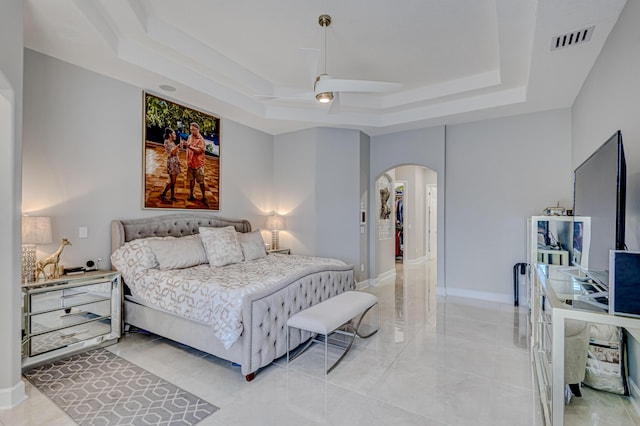 bedroom with ceiling fan and a tray ceiling