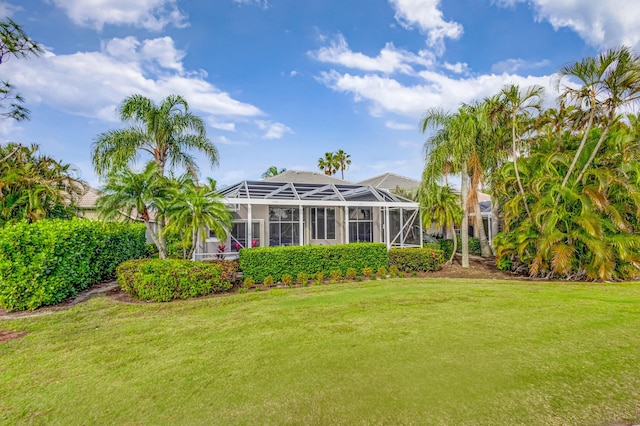 rear view of property with a lanai and a lawn