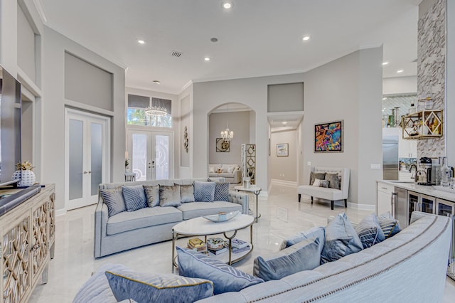 living room featuring a chandelier, sink, crown molding, and french doors