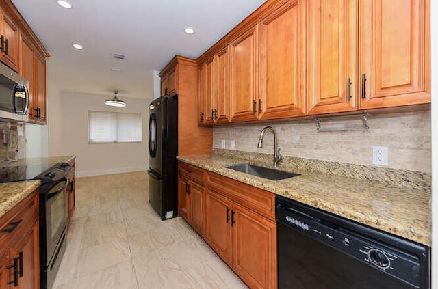 kitchen with light stone countertops, sink, tasteful backsplash, and black appliances