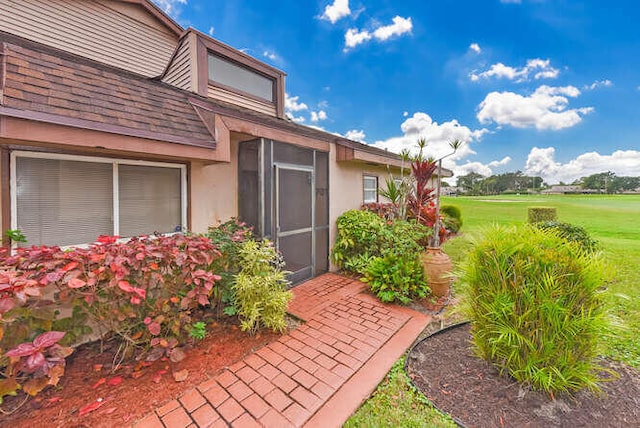 property entrance featuring a yard and stucco siding