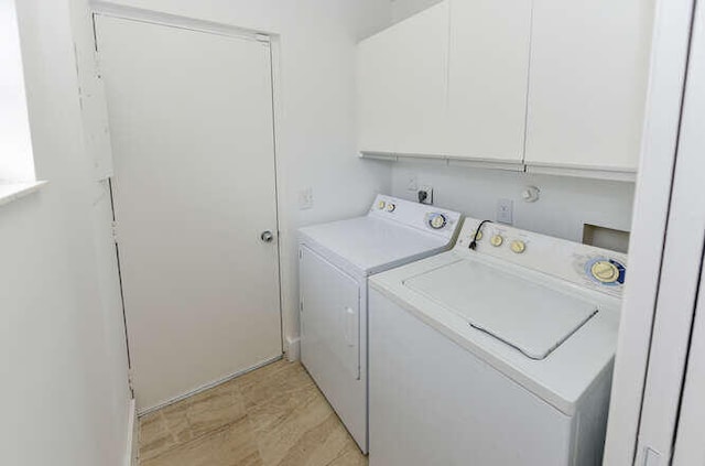 clothes washing area with cabinets and washing machine and clothes dryer